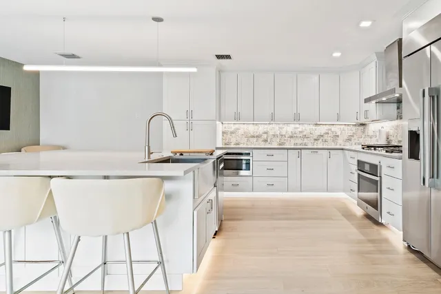 a kitchen with stainless steel appliances kitchen island granite countertop a dining table chairs and white cabinets