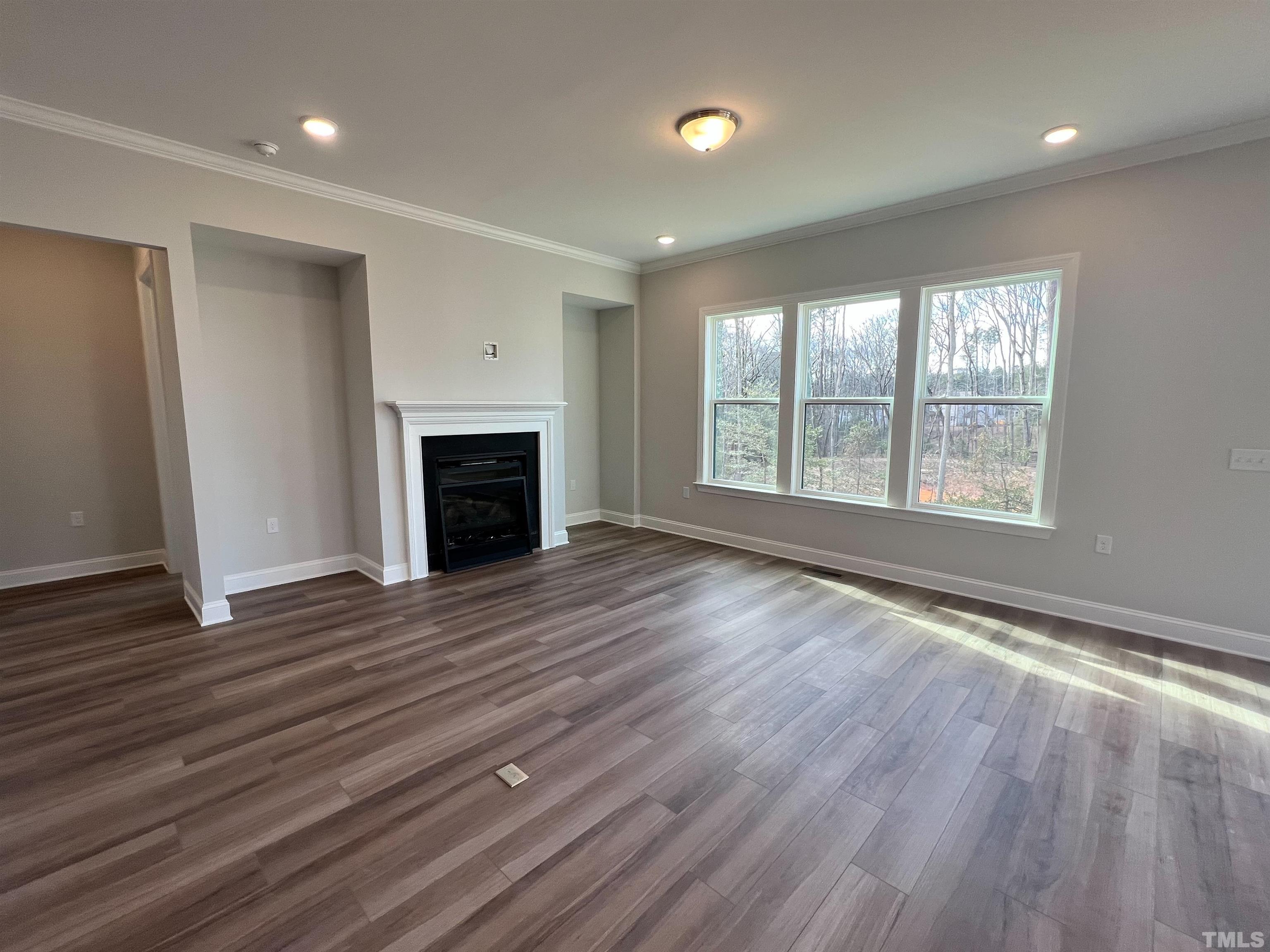 7613 Hasentree Way Wake Forest, NC 27587 - Photo 12 of 39 an empty room with wooden floor fireplace and windows