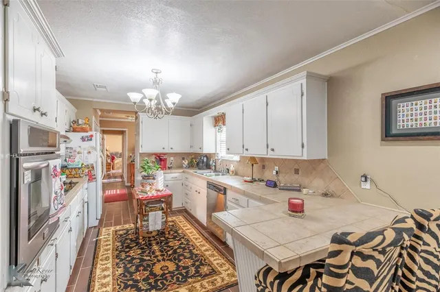 a room with stainless steel appliances furniture a rug and a chandelier