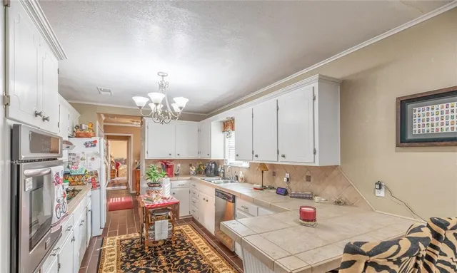 a open kitchen with stainless steel appliances granite countertop a stove a refrigerator a sink dishwasher and white cabinets with wooden floor