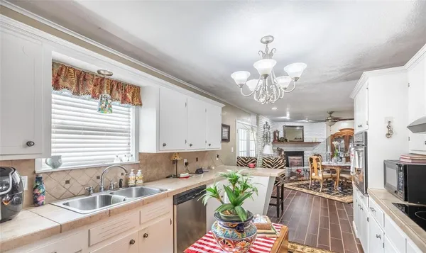 a kitchen with stainless steel appliances granite countertop a sink dishwasher a stove a refrigerator a dining table and chairs with wooden floor
