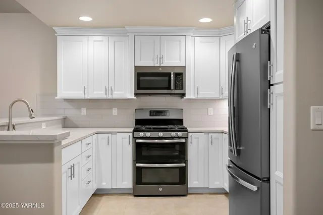 a kitchen with white cabinets and stainless steel appliances