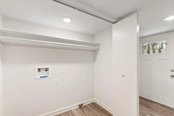 a view of a hallway with wooden floor and a bathroom