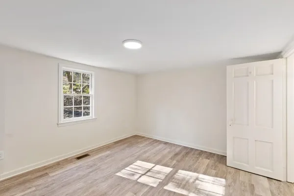 an empty room with wooden floor and kitchen