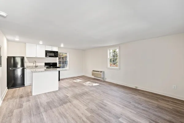 a kitchen with stainless steel appliances wooden floor and view living room