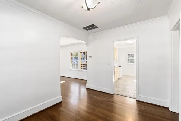 an empty room with wooden floor cabinet and windows