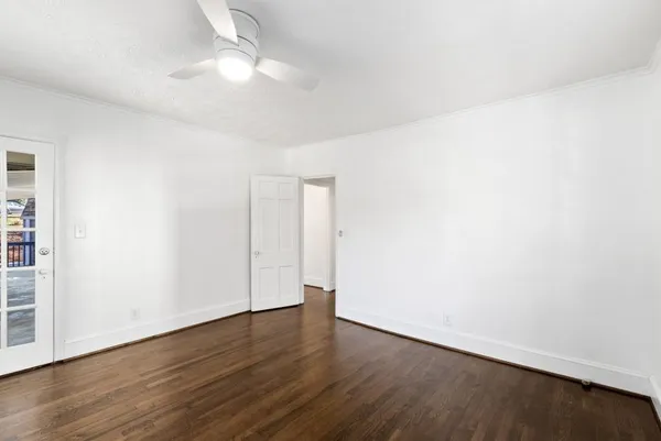 an empty room with wooden floor and fan