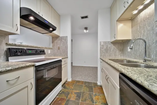 a kitchen with stainless steel appliances granite countertop a sink a stove and cabinets