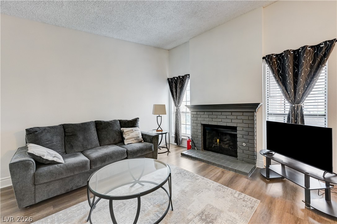 1751 East Reno Avenue, Unit 228 Las Vegas, NV 89119 - Photo 5 of 39 A comforting living room offers warm wood flooring and a classic brick fireplace.