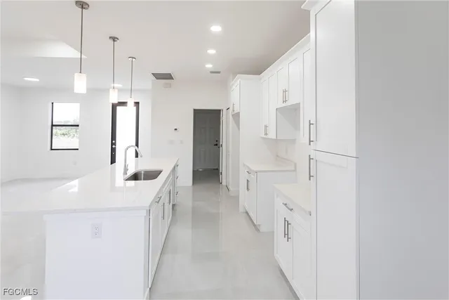 a large white kitchen with a sink and stainless steel appliances