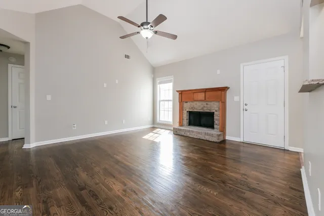 an empty room with wooden floor fireplace and windows