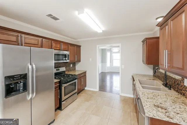 a kitchen with granite countertop a refrigerator stove and sink