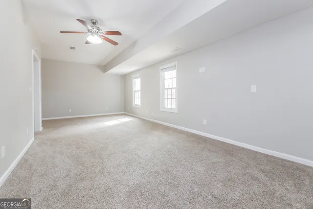 an empty room with windows and ceiling fan