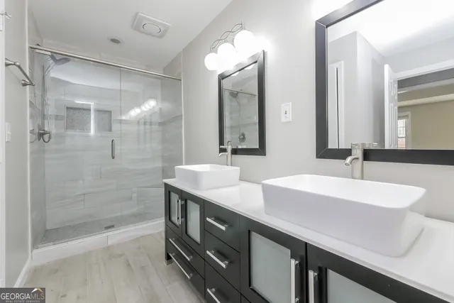 a bathroom with a double vanity sink mirror and shower
