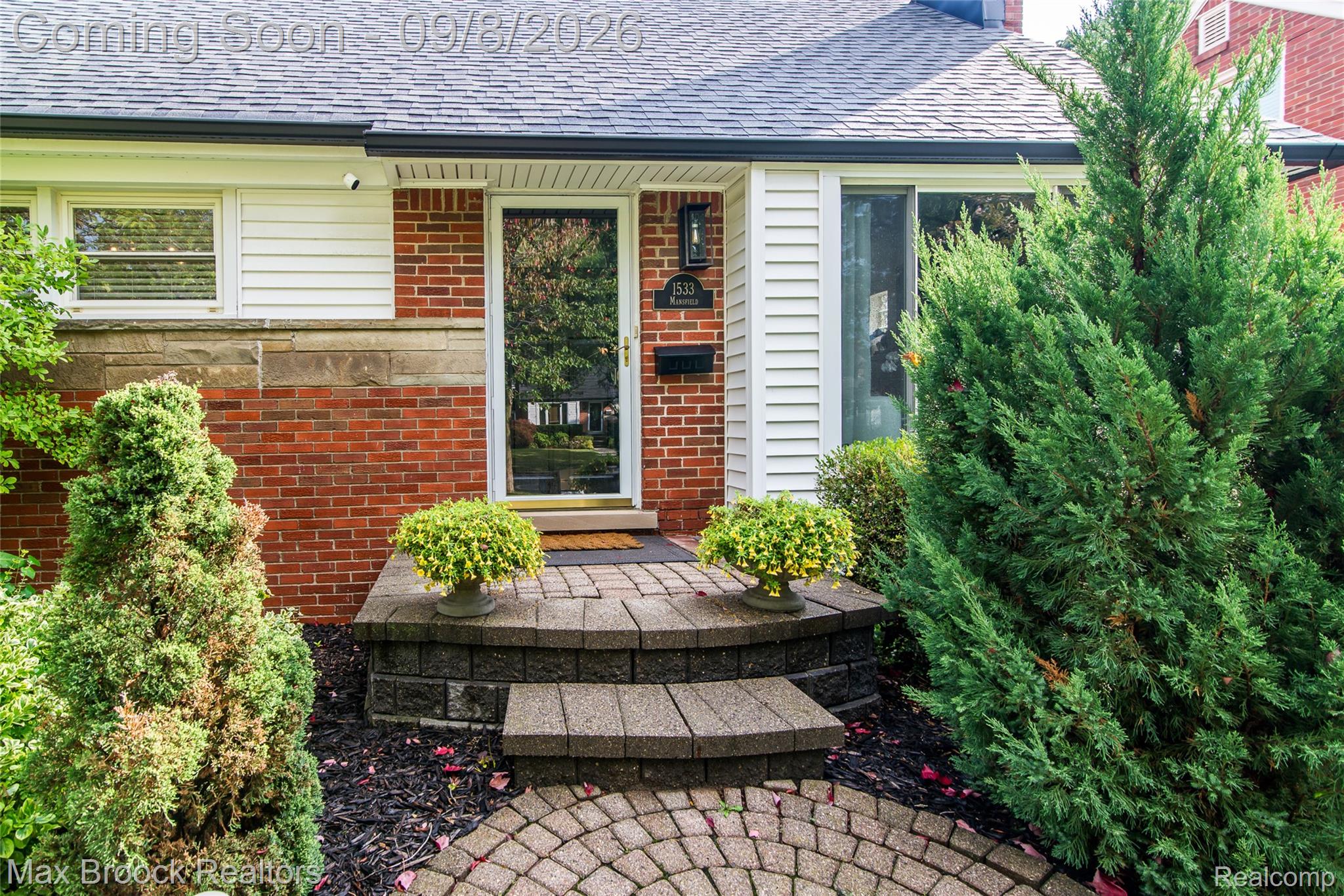 Brick and siding exterior featuring a multi-level paver pathway and natural stone accents