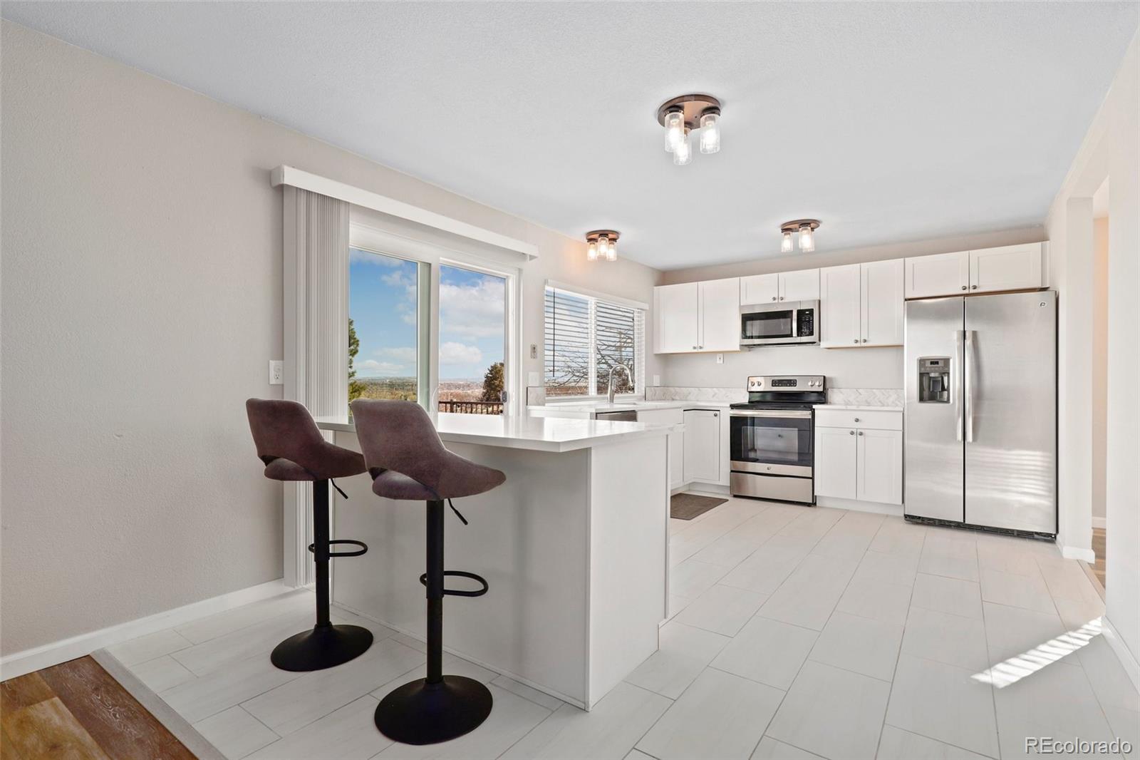 5484 South Cimarron Road Littleton, CO 80123 - Photo 16 of 40 a kitchen with stainless steel appliances kitchen island granite countertop a sink a refrigerator and chairs