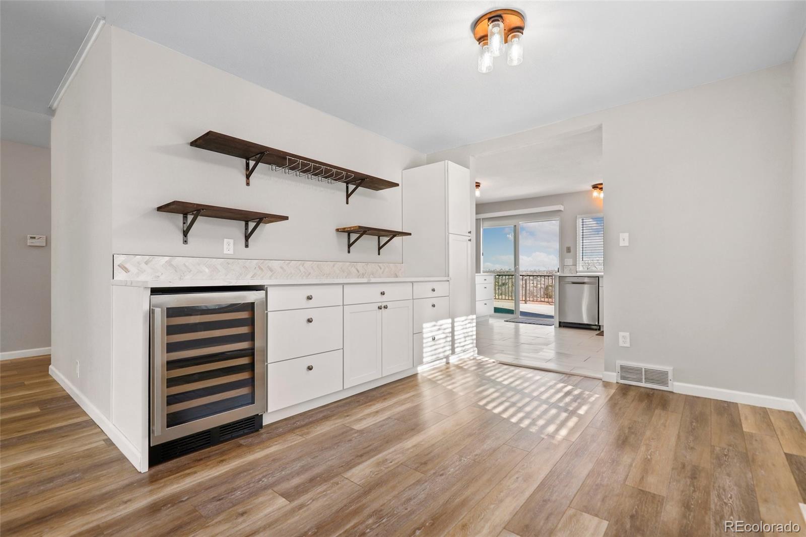5484 South Cimarron Road Littleton, CO 80123 - Photo 10 of 40 a kitchen with kitchen island white cabinets and wooden floor