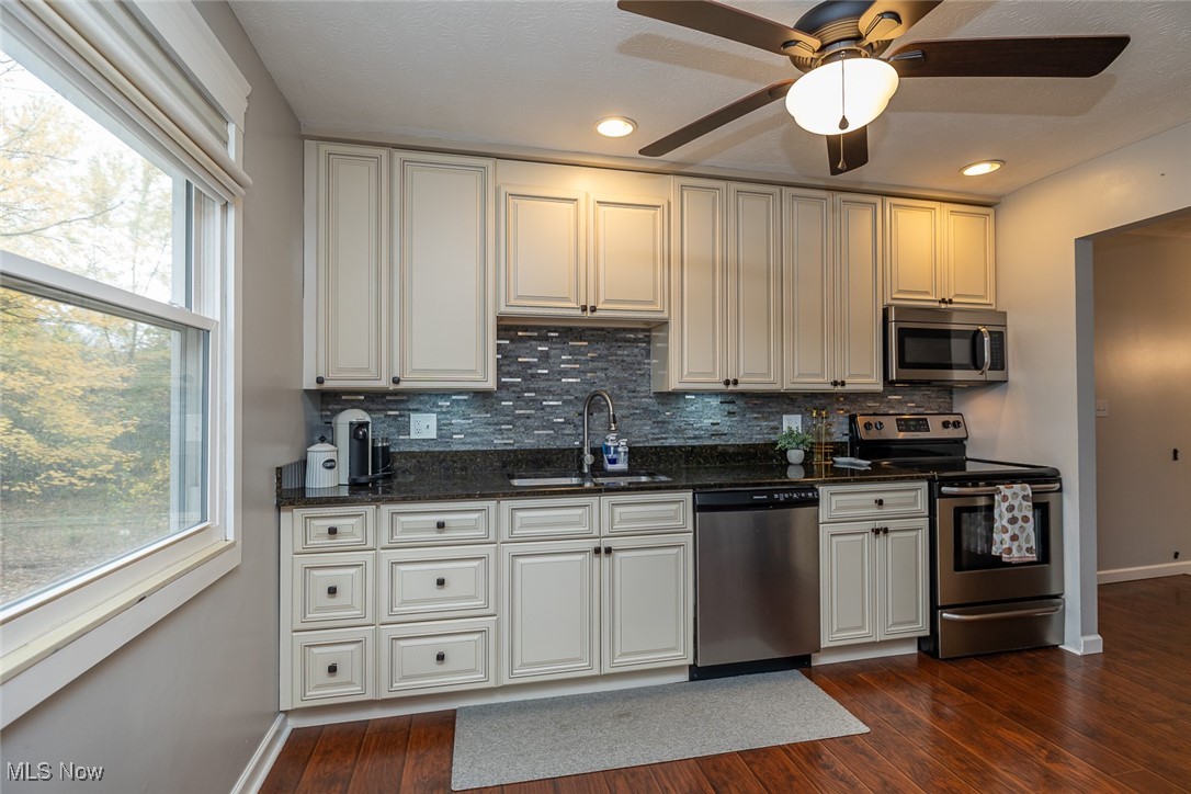 1060 Ledge Road Macedonia, OH 44056 - Photo 20 of 26 Kitchen with dark stone counters, sink, tasteful backsplash, appliances with stainless steel finishes, and dark hardwood / wood-style flooring