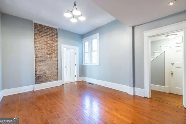 an empty room with wooden floor closet and windows