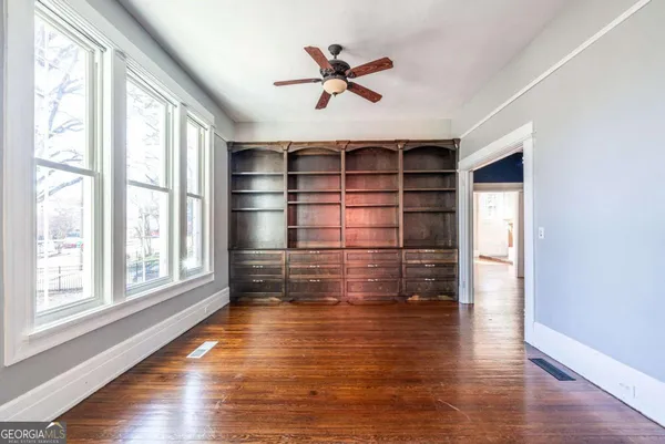 a view of empty room with wooden floor and fan
