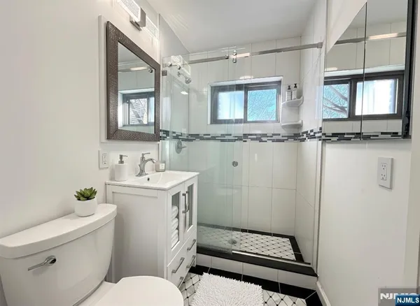 a bathroom with a sink a toilet a mirror and shower