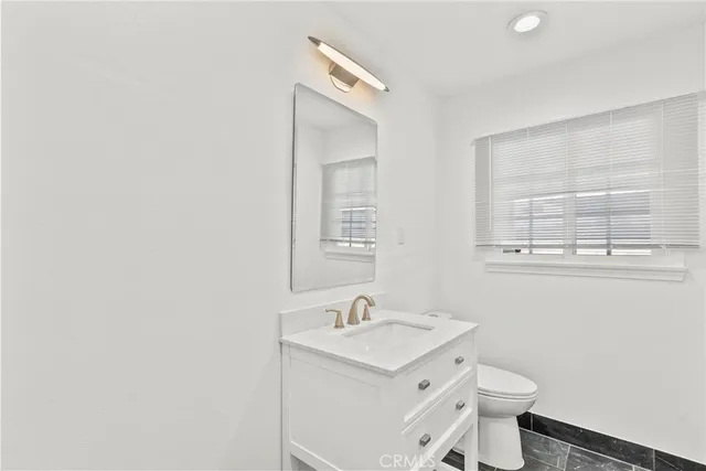 a room with stainless steel appliances kitchen island granite countertop a refrigerator and a sink