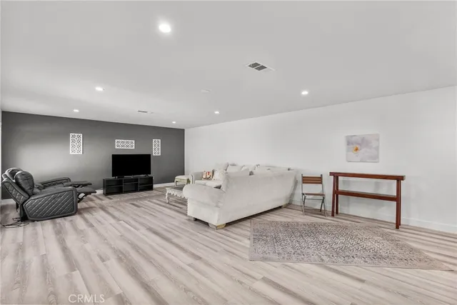 a living room with stainless steel appliances furniture a rug and a kitchen view