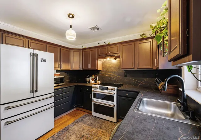 a kitchen with granite countertop a refrigerator stove and sink
