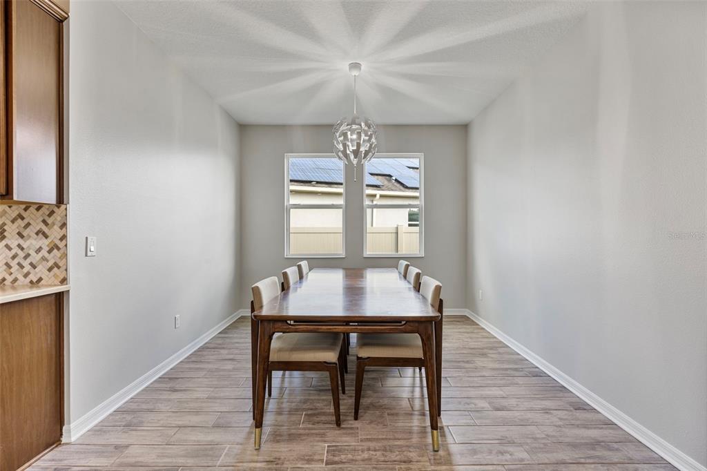 5356 Ragusa Loop St. Cloud, FL 34771 - Photo 4 of 69 a dining room with wooden floor a chandelier a wooden table and chairs