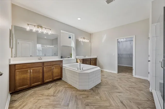 a spacious bathroom with a double vanity sink mirror and bathtub