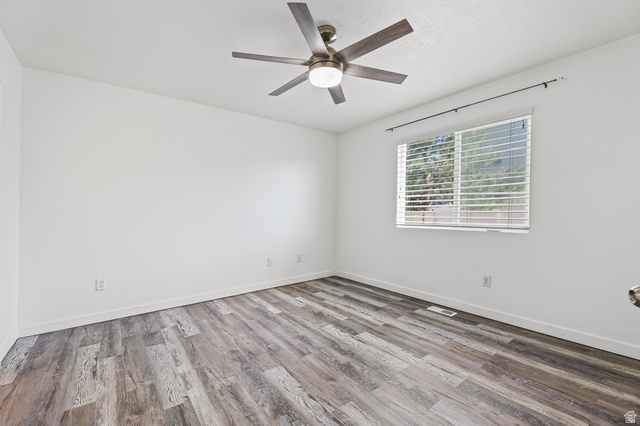 5525 Hampton Way Stansbury Park, UT 84074 - Photo 15 of 35 Room featuring wood-finish flooring, a window with blinds, a ceiling fan with light fixture, white walls, and white baseboards