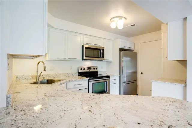 a kitchen with granite countertop a refrigerator stove and sink