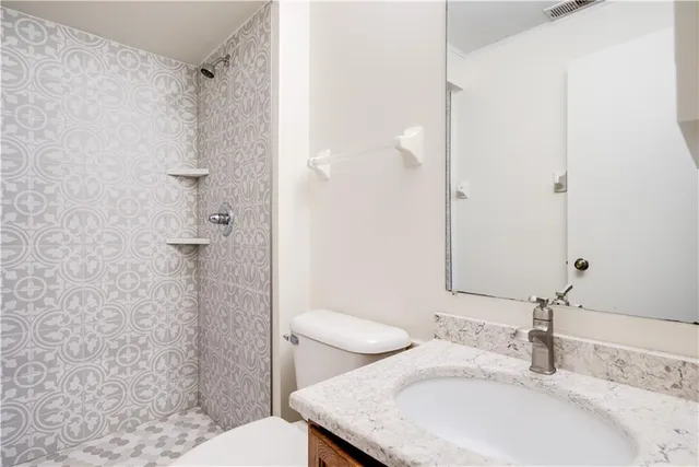 a bathroom with a granite countertop sink toilet and shower