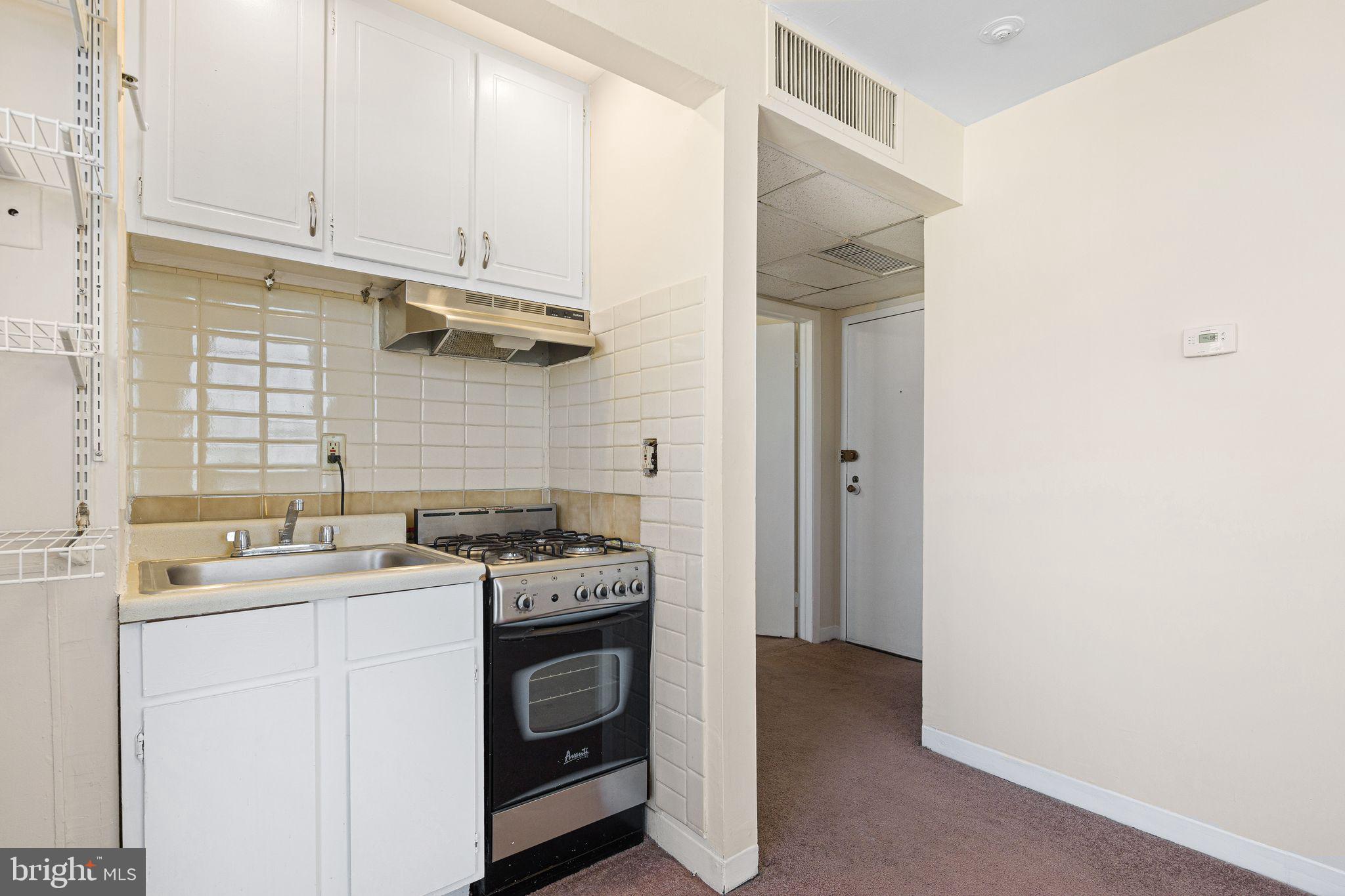 2135 Walnut Street, Unit 1103 Philadelphia, PA 19103 - Photo 7 of 18 a kitchen with a stove sink and cabinets