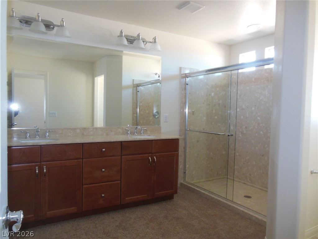 6390 Jackson Spring Road Las Vegas, NV 89118 - Photo 20 of 27 A well-lit primary bathroom provides a spacious double vanity and a glass-enclosed shower.