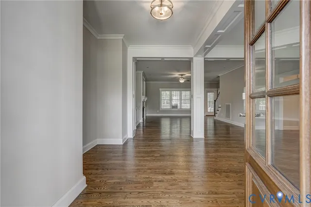 a view of an empty room with wooden floor and a window