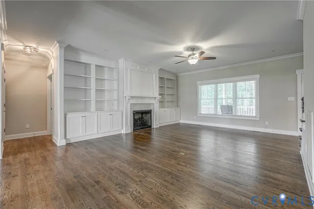 an empty room with wooden floor fireplace and windows