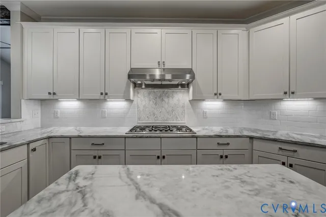 a kitchen with granite countertop a stove and white cabinets