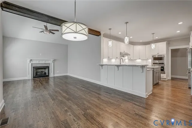 a kitchen with stainless steel appliances granite countertop a stove top oven a refrigerator and a fireplace with wooden floor