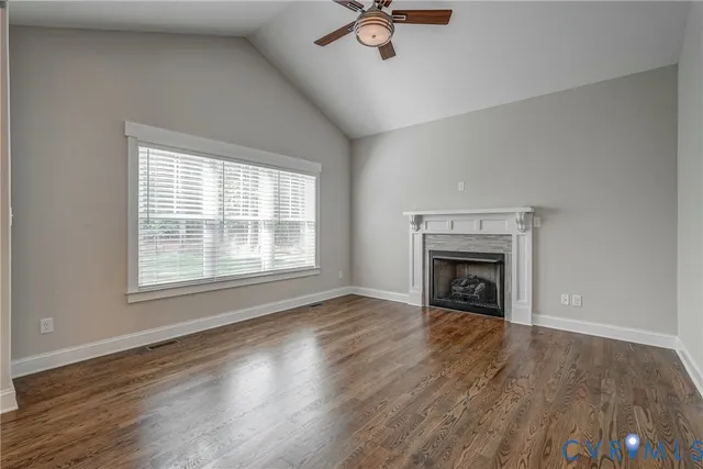 a view of an empty room with wooden floor fireplace and a window
