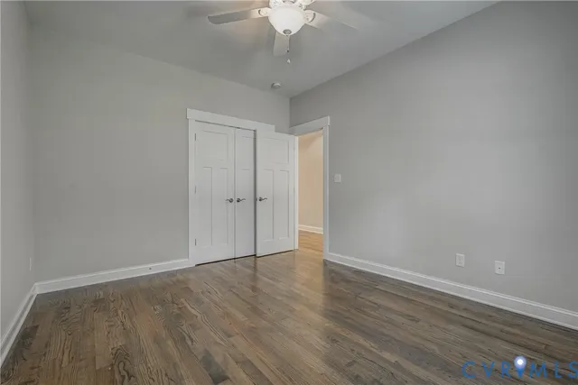 a view of an empty room with wooden floor and a chandelier fan