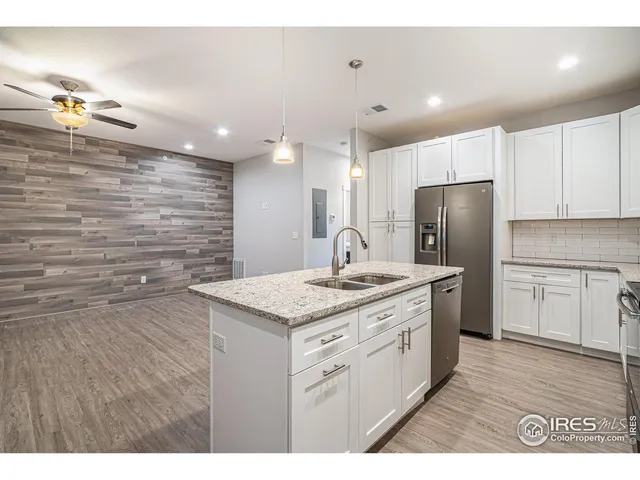 a kitchen with a sink a refrigerator and white cabinets