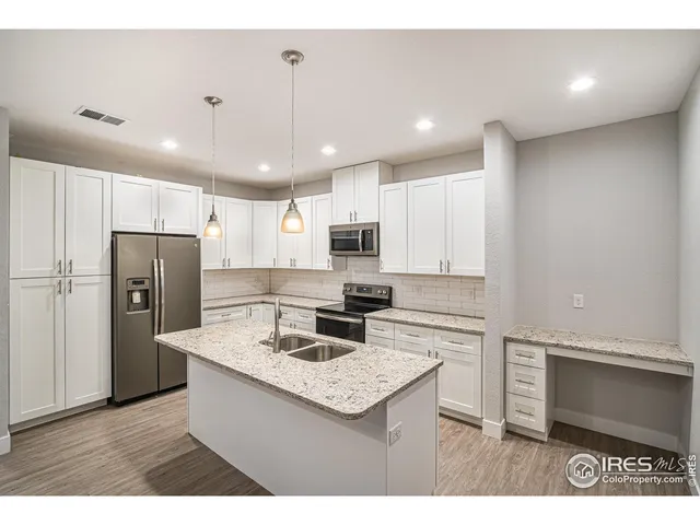 a kitchen with stainless steel appliances granite countertop a kitchen island a stove a refrigerator a sink and a refrigerator