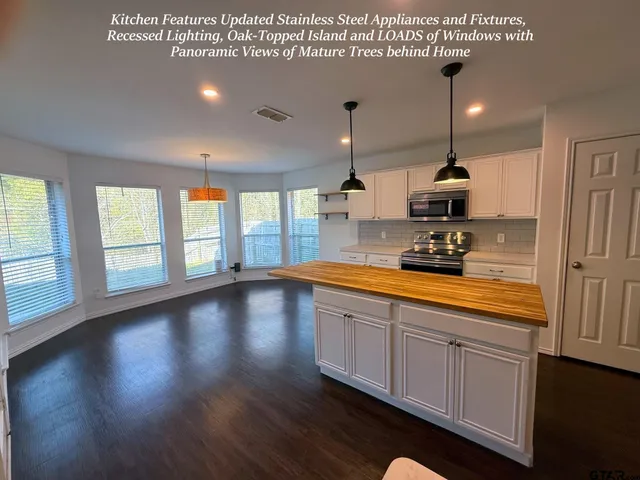 a view of large kitchen with stainless steel appliances granite countertop a sink a stove and a wooden floors