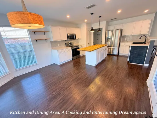 a large kitchen with stainless steel appliances wooden floors and wooden cabinets