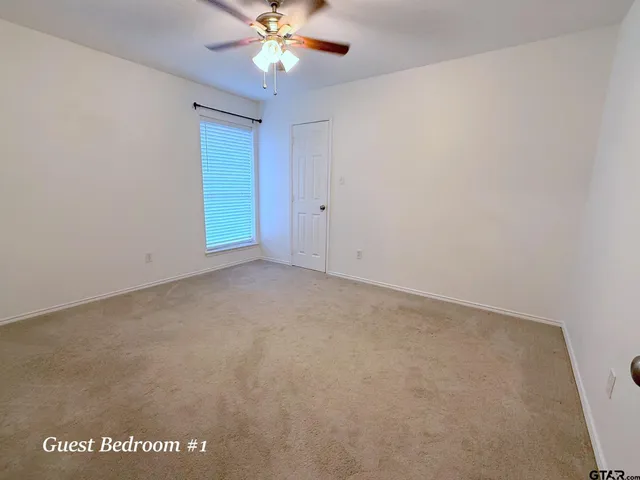 a view of an empty room with a chandelier fan