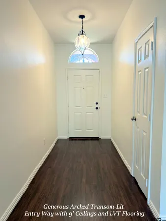 an empty room with wooden floor chandeliers and hallway