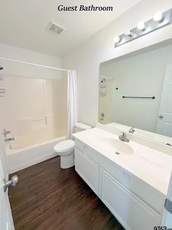 a spacious bathroom with a granite countertop sink a toilet and a bathtub