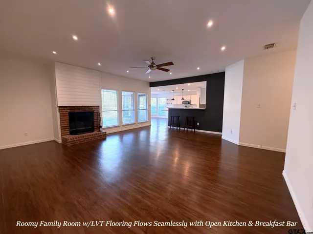 an empty room with wooden floor fireplace and windows
