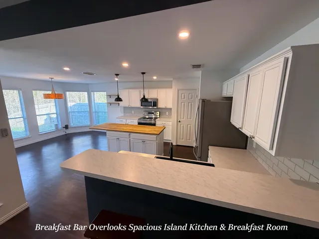 a kitchen with stainless steel appliances a refrigerator a sink dishwasher with a dining table and wooden floor